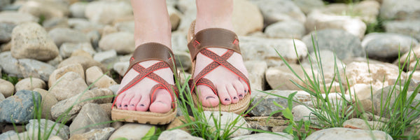 Model wearing Riley Everywear Sandal in Walnut walking on stones