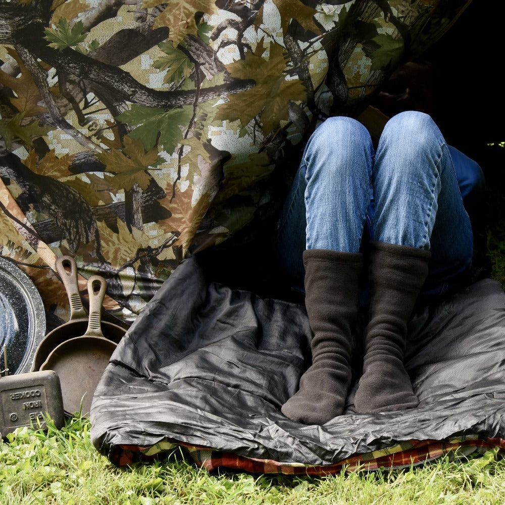 Versafit Fleece Cabin Socks in Black on-figure. Model sitting with their legs sticking out of a tent flap