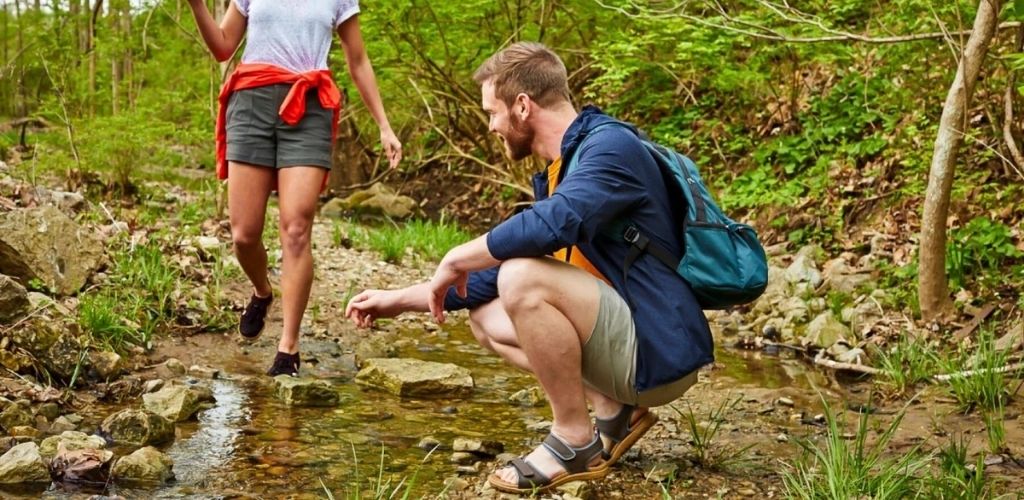 A man and a woman walking through a creek