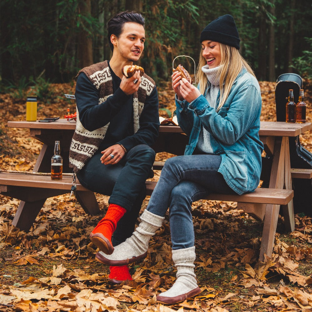 Male and Female model wearing the Grey and Red Ragg Wool Slipper Socks as they enjoy a meal together at their campsite