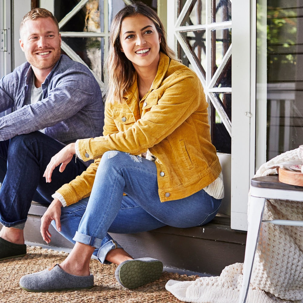 Women’s Parker Hoodback Slipper + BLOOM™ in Ash Grey on model sitting on a porch with a male model