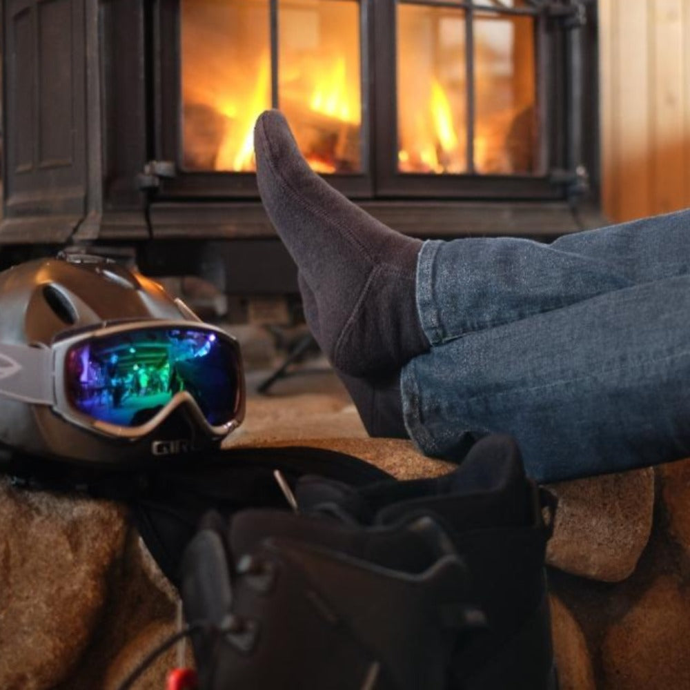 Man by Fire after Snowboarding in cozy cabin wearing charcoal versafit socks