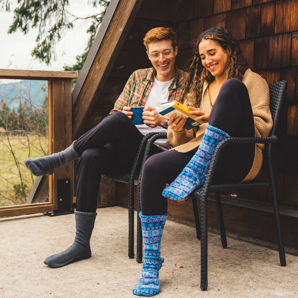 Couple sitting out on a porch wearing the Charcoal and Icelandic Blue Versafit socks. Reading and sipping coffee.