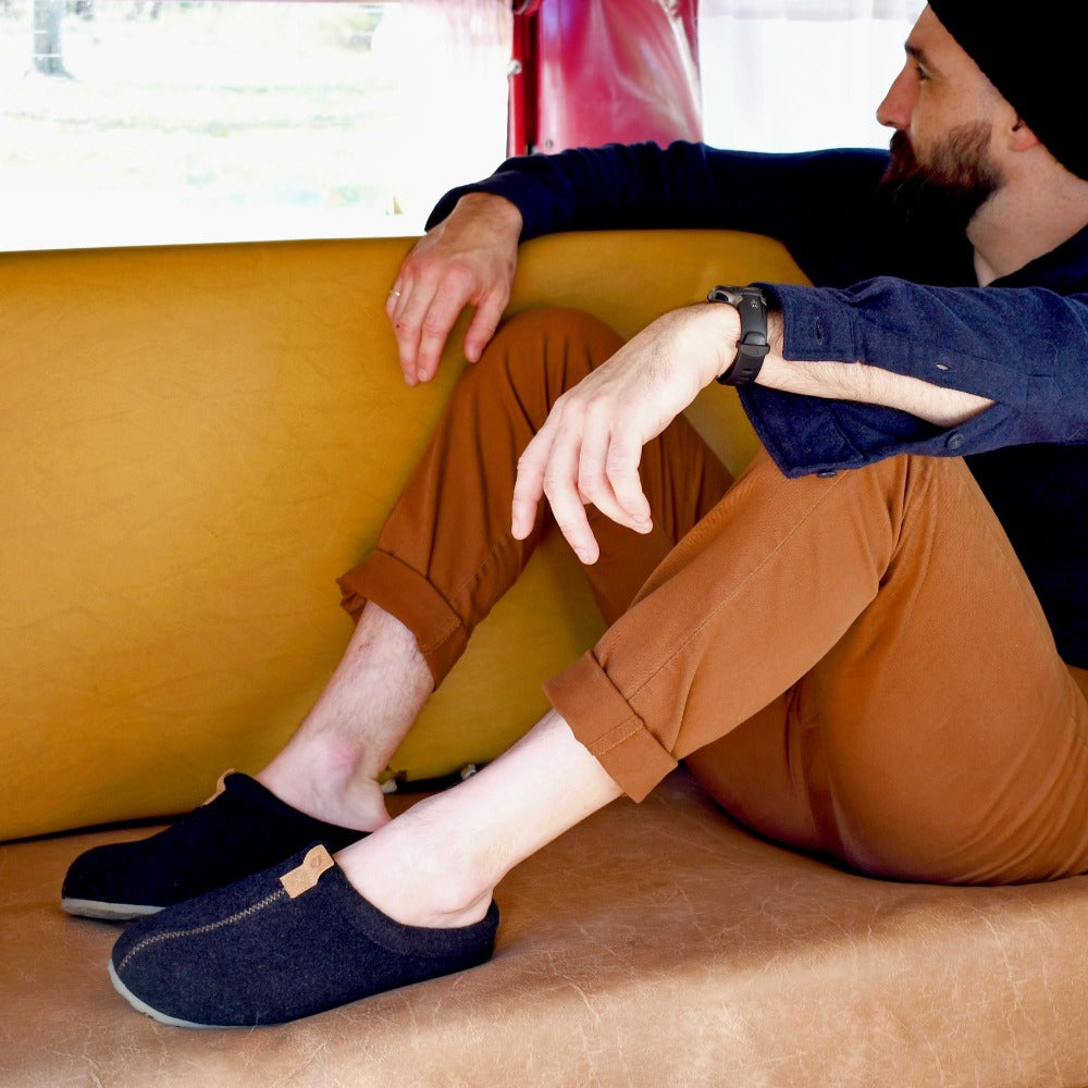 Men’s Algae-Infused Wool Slippers on figure. Male model sitting in converted van wearing slippers