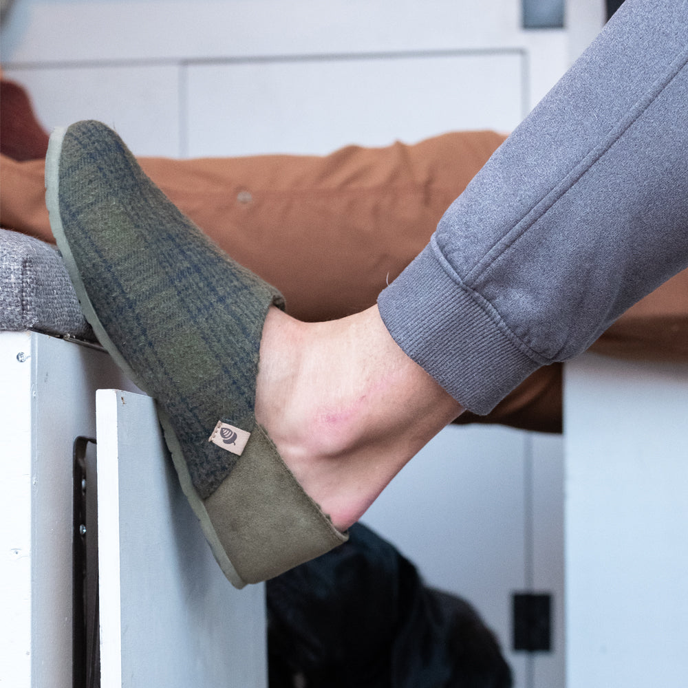 Men’s Algae-Infused Parker Slippers in Olive on Figure. Model has their leg up on a ledge